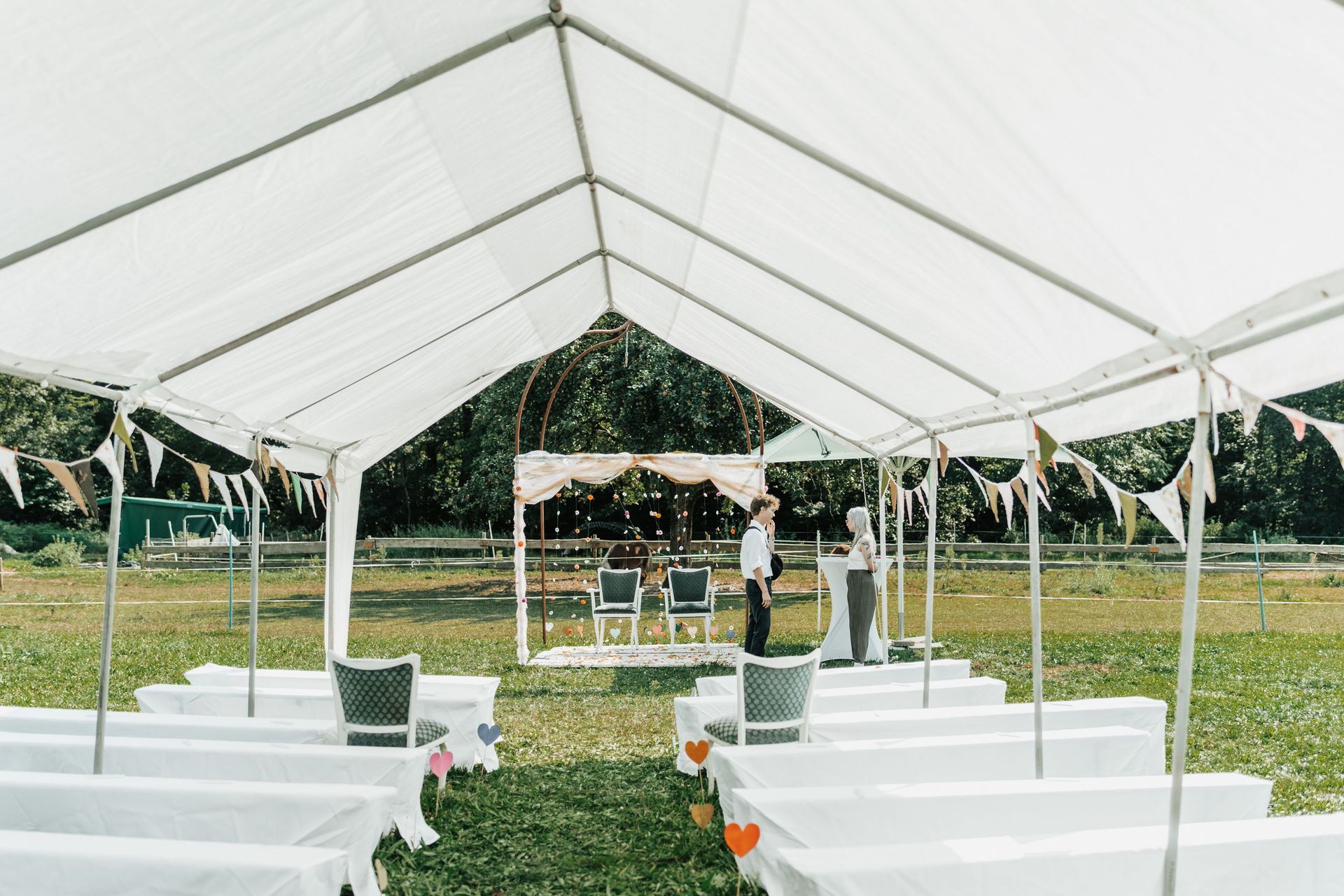 A beautiful outdoor wedding setup under a white tent with chairs and decoration.